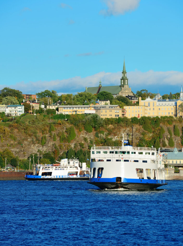 Ferry boat in river in Quebec City with blue sky.